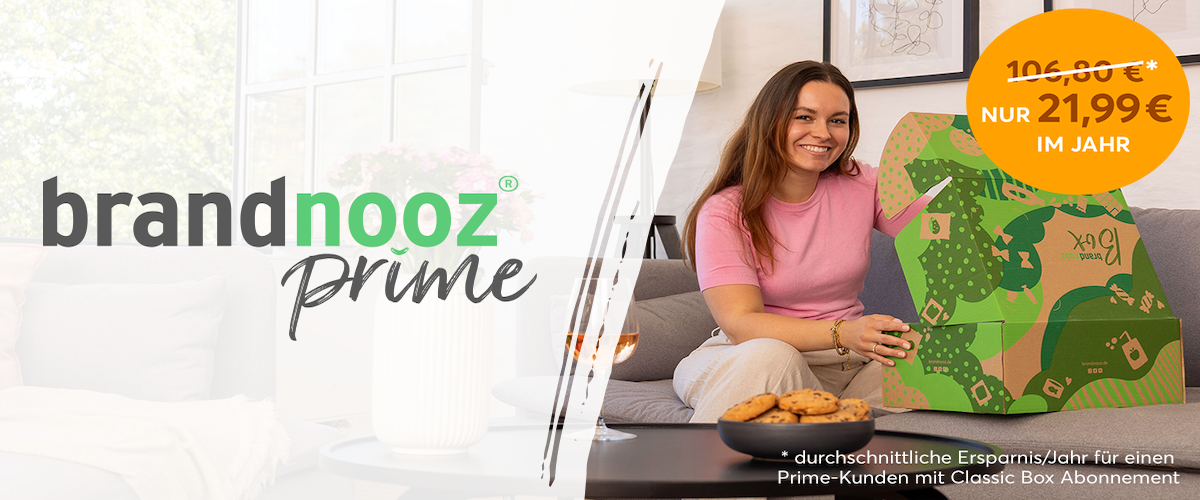 Auf dem Banner steht links: neu, brandnooz Prime, Jetzt Mitglied werden und Gratis Box, sowie viele Vorteile sichern. Rechts sitzt eine Frau auf einer Couch und freut sich, eine brandnooz Box zu öffnen.