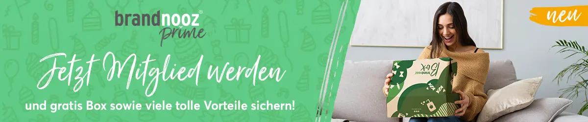 Auf dem Banner steht links: neu, brandnooz Prime, Jetzt Mitglied werden und Gratis Box, sowie viele Vorteile sichern. Rechts sitzt eine Frau auf einer Couch und freut sich, eine brandnooz Box zu öffnen.