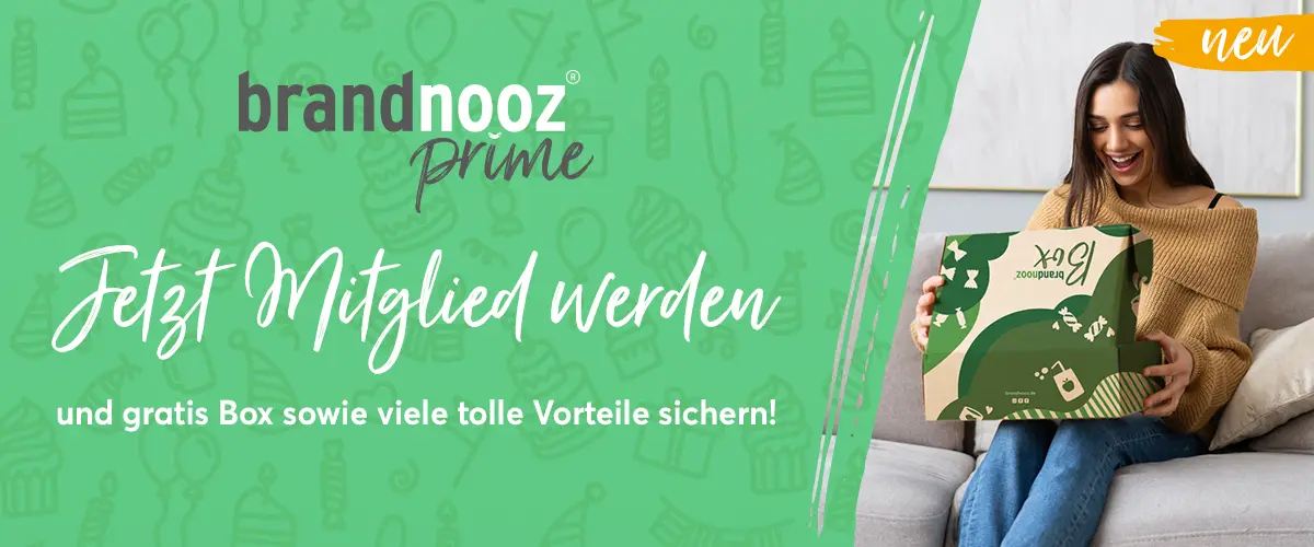Auf dem Banner steht links: neu, brandnooz Prime, Jetzt Mitglied werden und Gratis Box, sowie viele Vorteile sichern. Rechts sitzt eine Frau auf einer Couch und freut sich, eine brandnooz Box zu öffnen.